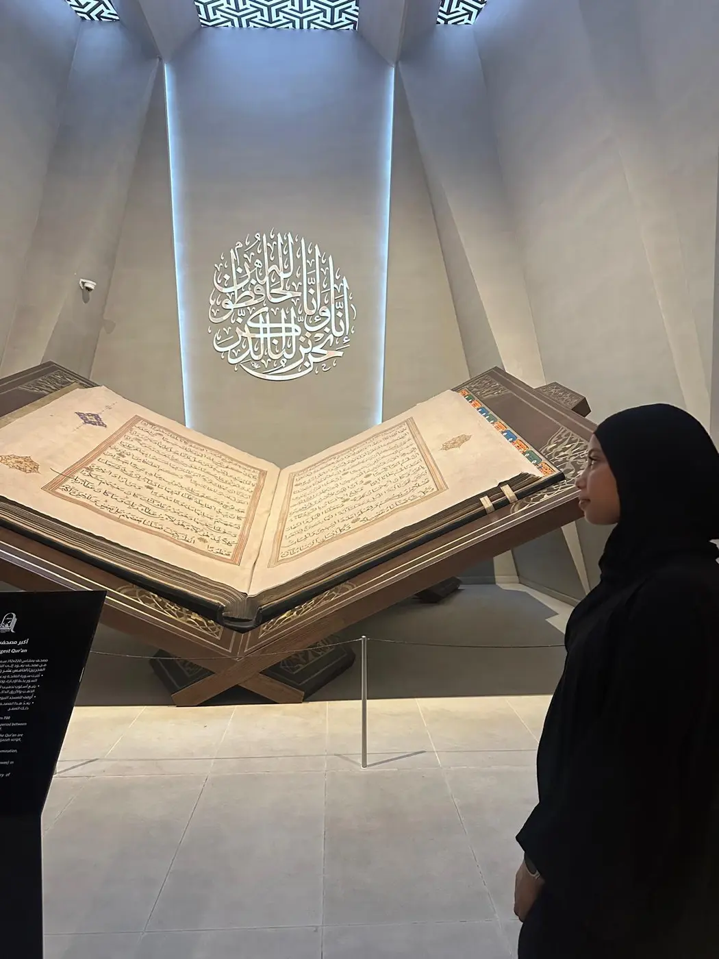 طالبة تتأمل مصحفًا معروضًا